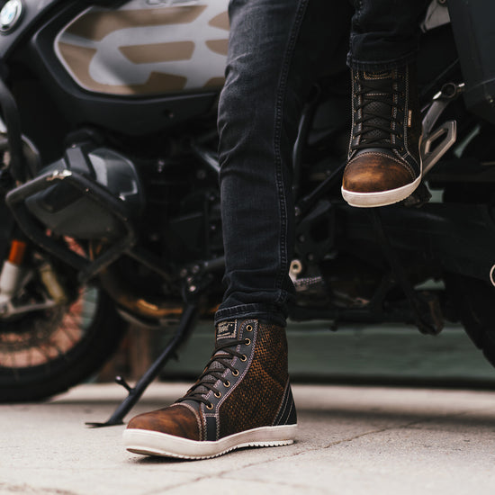 Person wearing brown ventilated motorcycle boots standing next to a  BMW GS motorcycle.