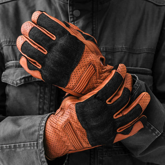 Top view of black denim and camel brown leather motorcycle gloves showing reinforced knuckles, perforated leather wrist panels, and durable construction for motorcycle riding