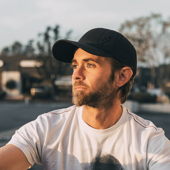Man wearing a black baseball cap and white t-shirt with blurred background