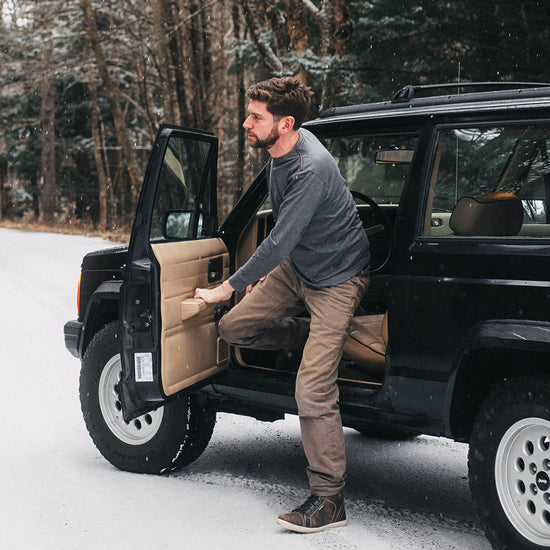 Man getting into a black vintage Jeep Cherokee SUV in a snowy forest