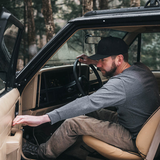 Man closing a Jeep Cherokee car door wearing a gray long-sleeve shirt and brown pants.