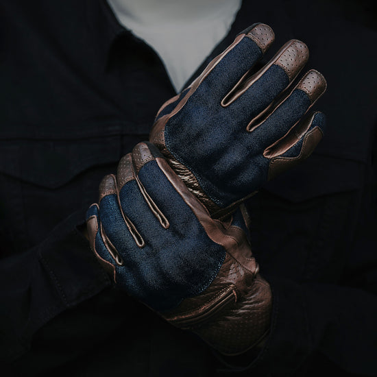 Pair of brown leather and blue denim gloves on a dark background