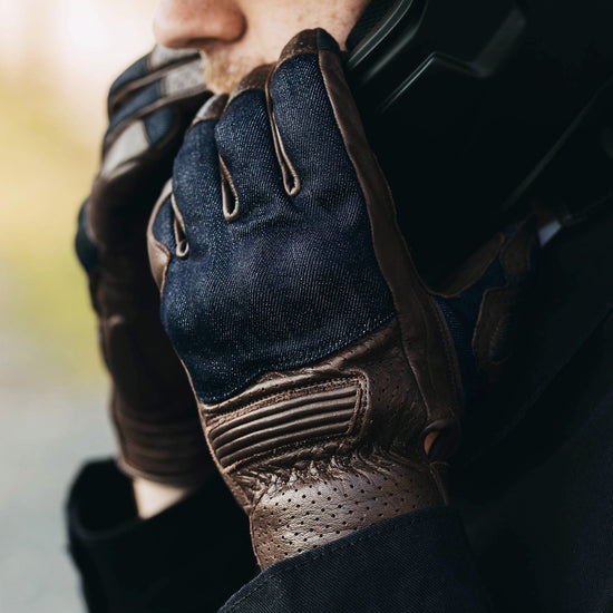 Close-up of a person wearing a dark blue and brown glove on a blurred background