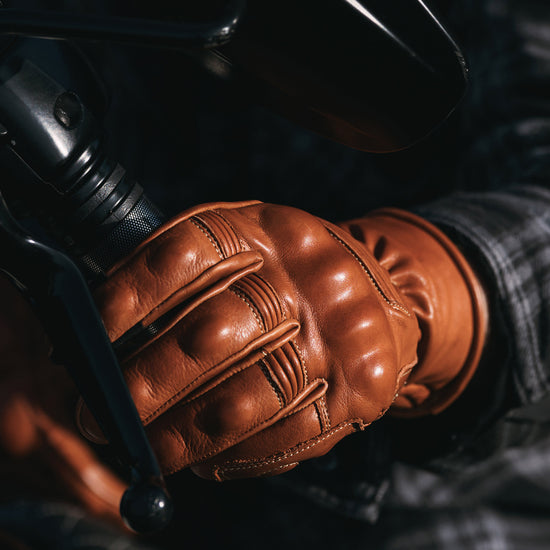 Golden Brown leather glove on a motorcycle handlebar