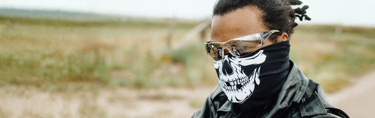 Motorcyclist wearing a black-and-white skull face mask, protective glasses and a black leather jacket.