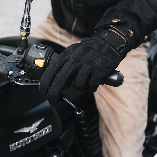 Indie Ridge black Powersport motorcycle glove on Moto Guzzi handlebars, showing breathable mesh, protective knuckle design, and secure wrist closure.